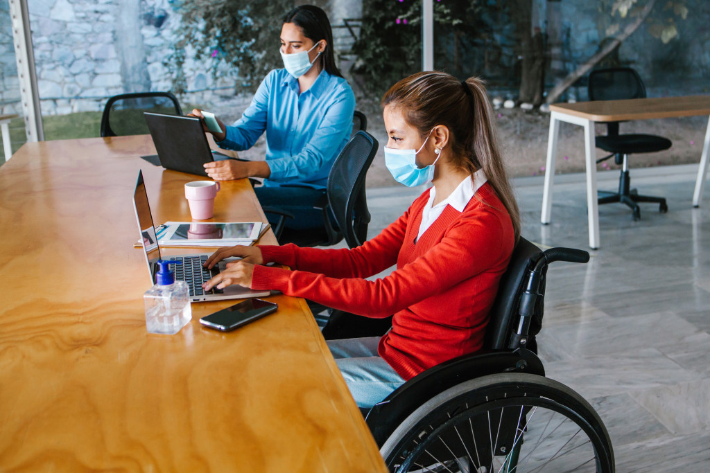 Young Latin woman in wheelchair working with another woman colleague at their workplace